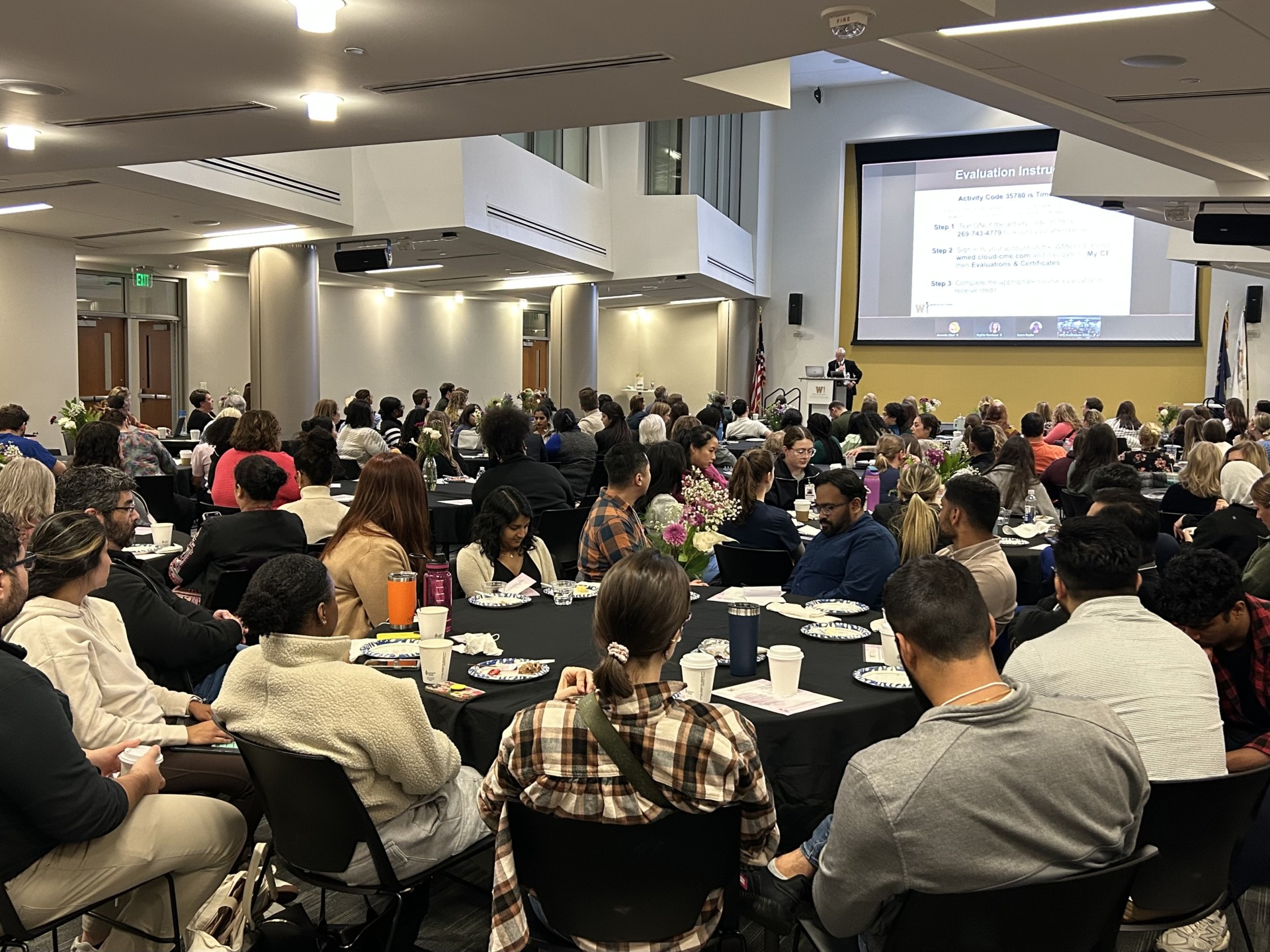 Photo of people sitting at tables inside the William D. Johnston and Ronda E. Stryker Auditorium during the fourth annual Well-Being Promotion Symposium