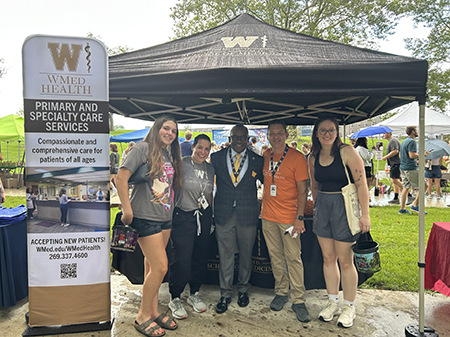WMed Dean J. Adrian Tyndall smiles for a photo with WMU students and WMed Health clinical leaders