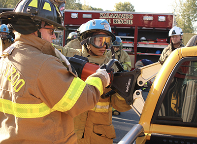 An emergency medicine resident uses extrication tools to open a car door