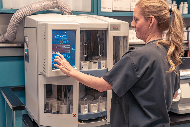 Histotechnologist Kristi Bailey adjusts settings on staining machine