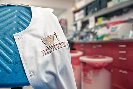 A WMed lab coat is shown draped over a chair