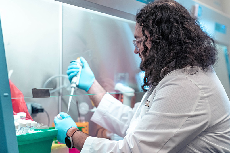 Christopher Jondle, PhD, measures and transfers samples in his lab