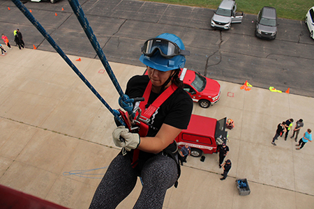 A medical student rappels down the side of a building during the MFR capstone event